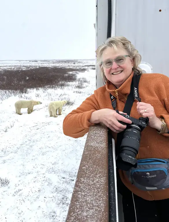 Smiling photographer on the lodge deck with two polar bears behind her